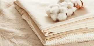 What Is Supima Cotton? The Softest Cotton Explained Natural cotton fabrics stacked neatly beside soft cotton bolls, showing a breathable alternative to synthetic materials and exploring the question — does polyester make you sweat.what is supima cotton