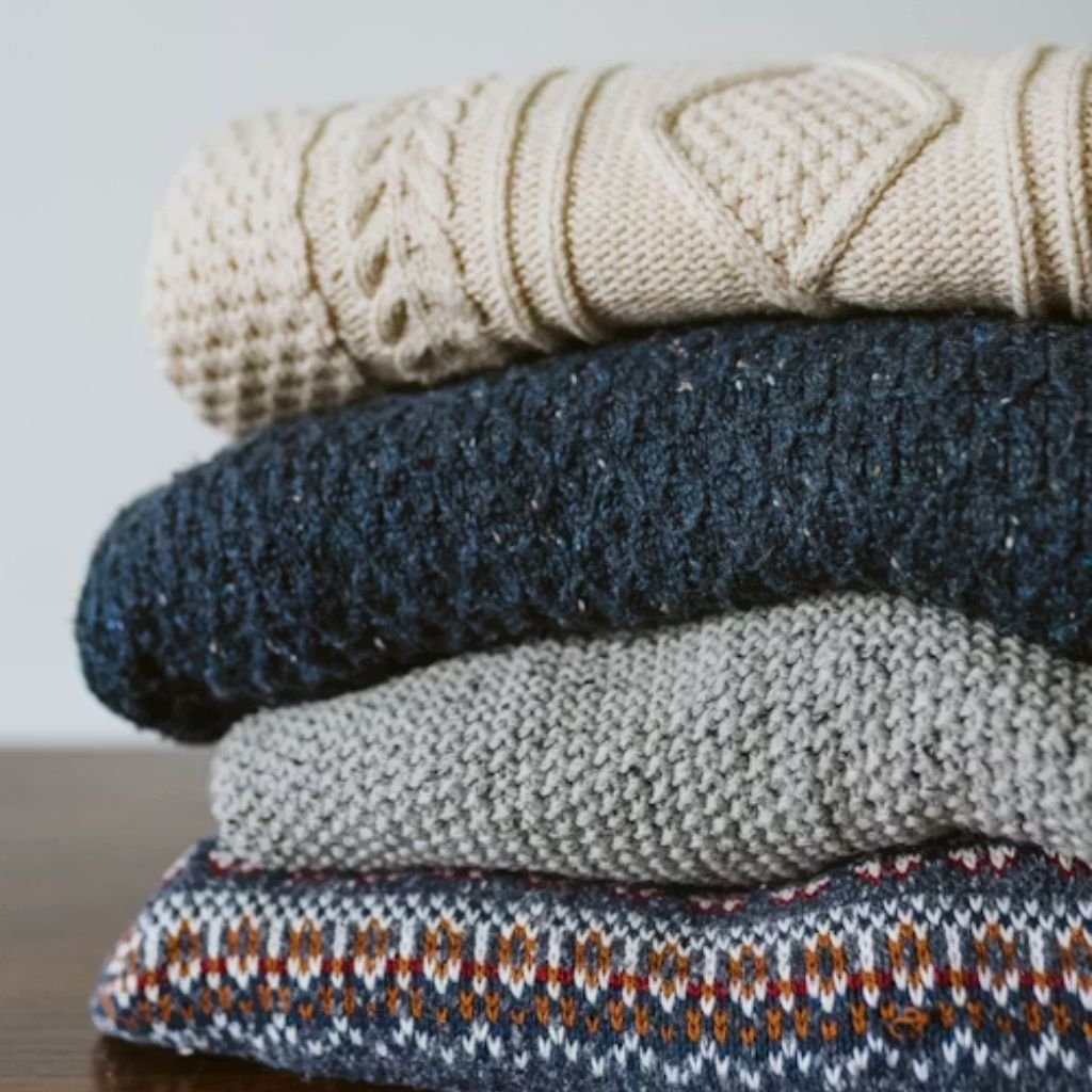 History of Winter Fashion Trends and How They Evolved Today! 9 Two women showcasing winter fashion: one wearing a brown teddy coat with a red-and-green plaid scarf in a snowy outdoor setting, and another walking in an urban street wearing a long red coat, white turtleneck, gray pants, and carrying a white handbag.History of Winter Fashion Trends