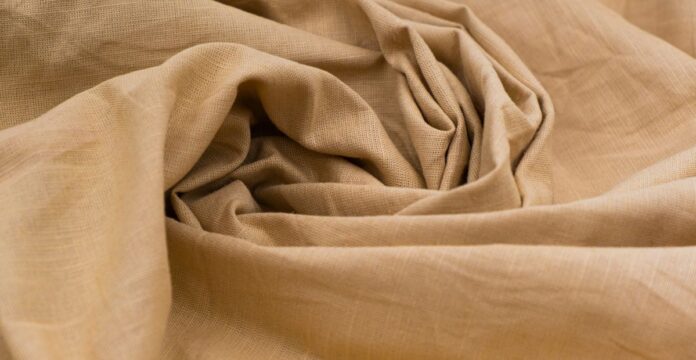 Close-up of beige polyester fabric with soft folds and texture, illustrating the question — does polyester make you sweat during wear.Does Cotton Fabric PillDoes Cotton Fabric Pill