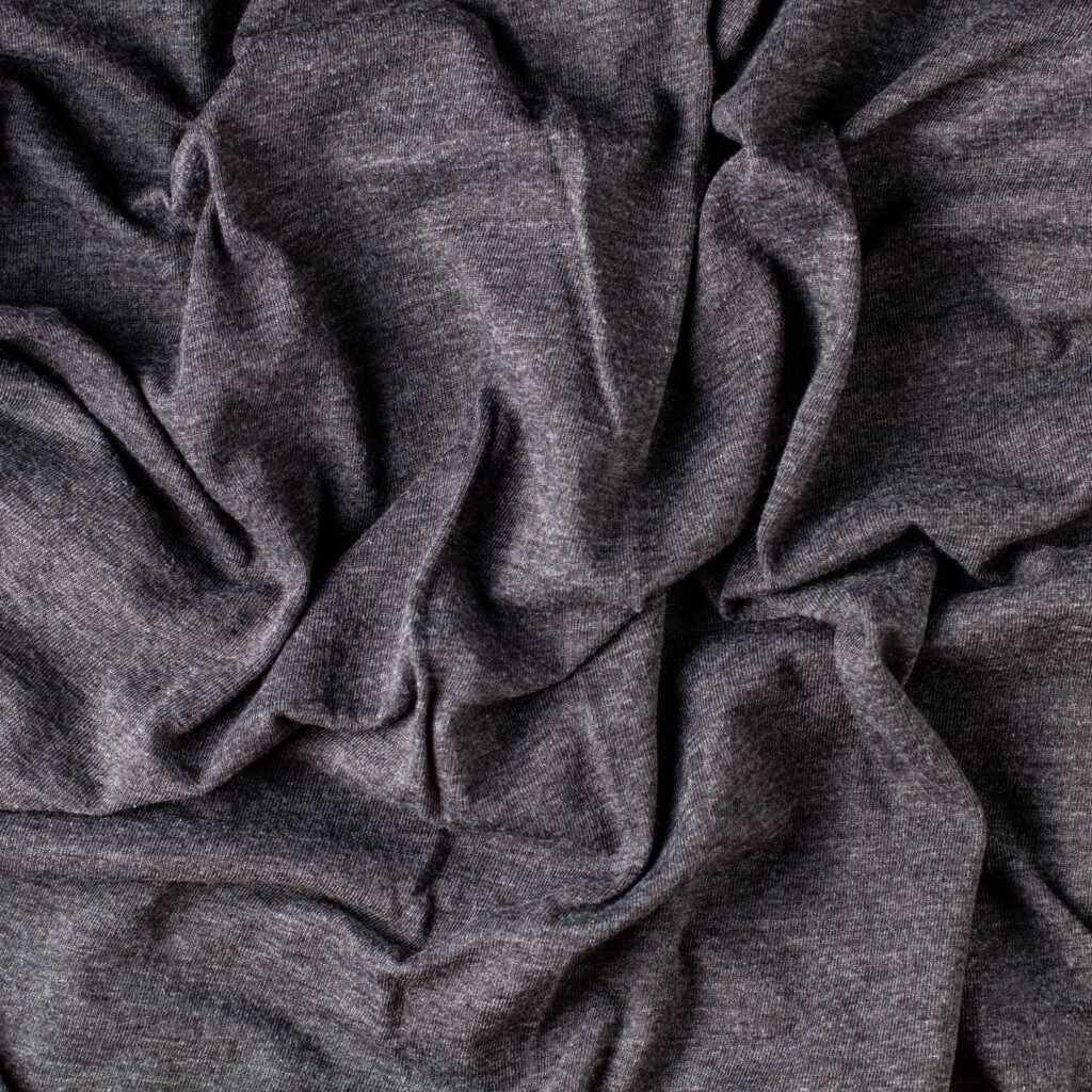 Close-up of soft, heathered dark gray fabric with a smooth drape and gentle folds.Is rayon a good fabric