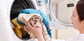 Does Cotton Shrink in the Dryer? (And How to Prevent It!) A woman loading colorful clothes into a dryer, illustrating the question — does polyester make you sweat more during daily wear.does cotton shrink in the dryerdoes cotton shrink in the dryer