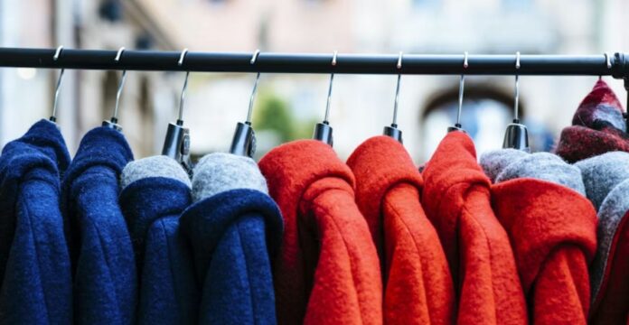 A stack of neatly folded knitted sweaters in gray, cream, and mustard colors showing various textured patterns.Types of Winter Fashion Trends