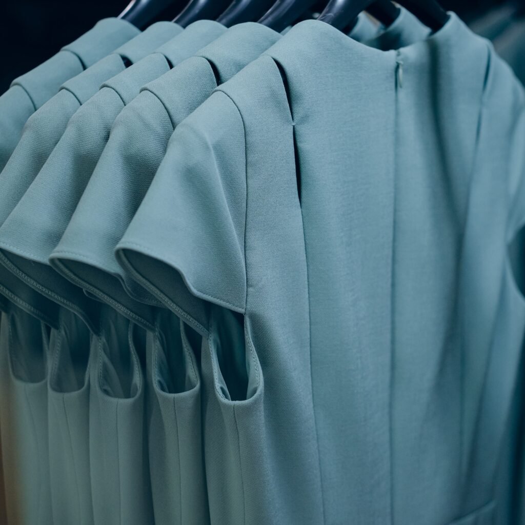 Rows of light teal rayon dresses hanging on racks, showcasing soft drape and smooth fabric.