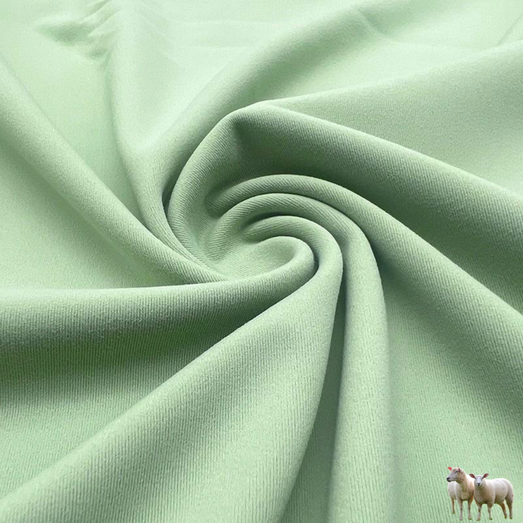 A soft mint-green fabric is twisted into a central spiral, creating folds and gentle texture. In the bottom-right corner, a small group of three sheep silhouettes stands, adding a whimsical touch.