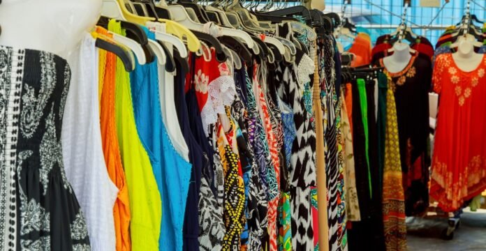 A crowded clothing rack filled with a variety of colorful dresses and tops hanging on hangers. Cotton Dresses