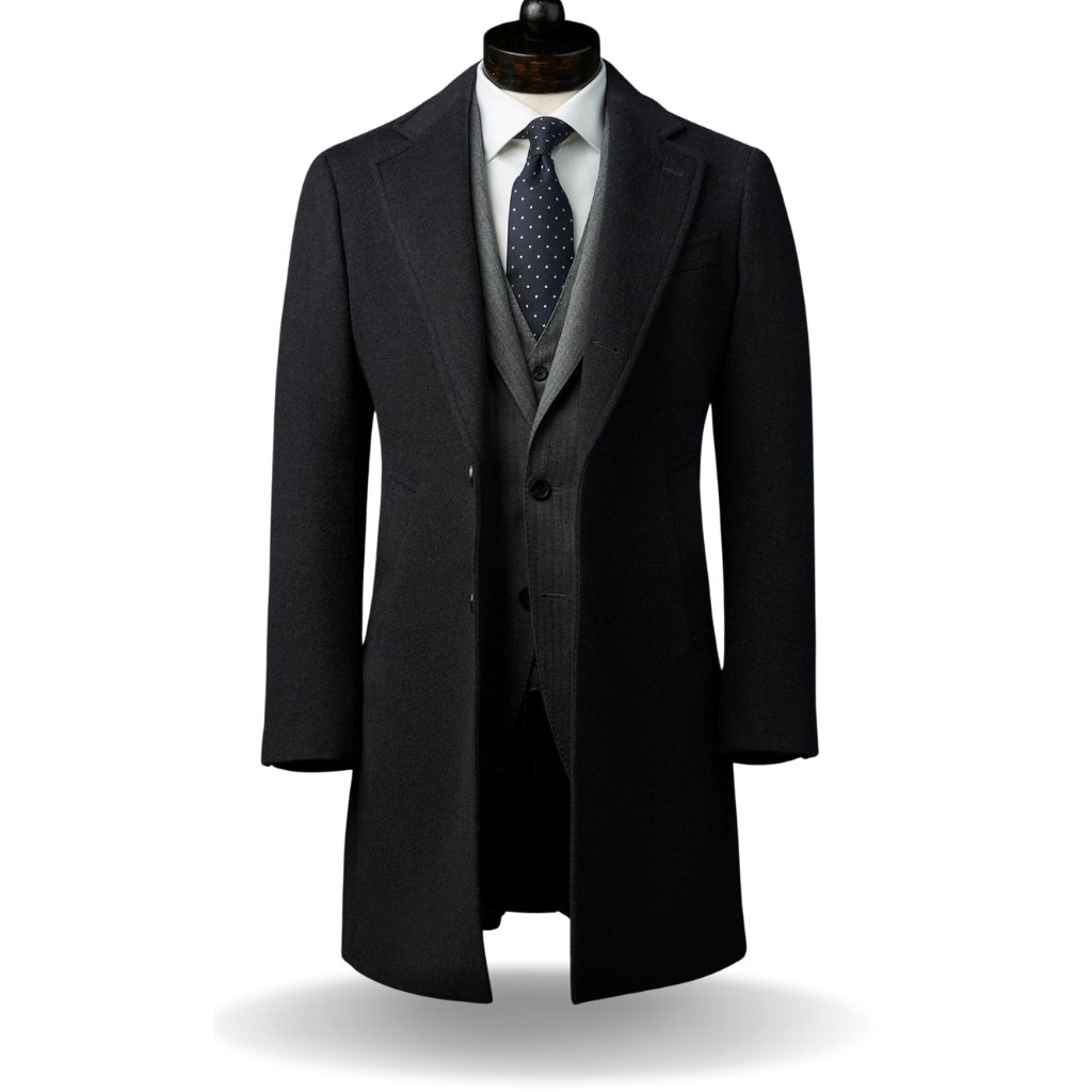 Topcoat Jackets Stylish Outerwear for a Sharp Seasonal Look 12 Dark men's overcoat displayed on a dress form, worn over a gray waistcoat and white shirt with a navy polka-dot tie.
