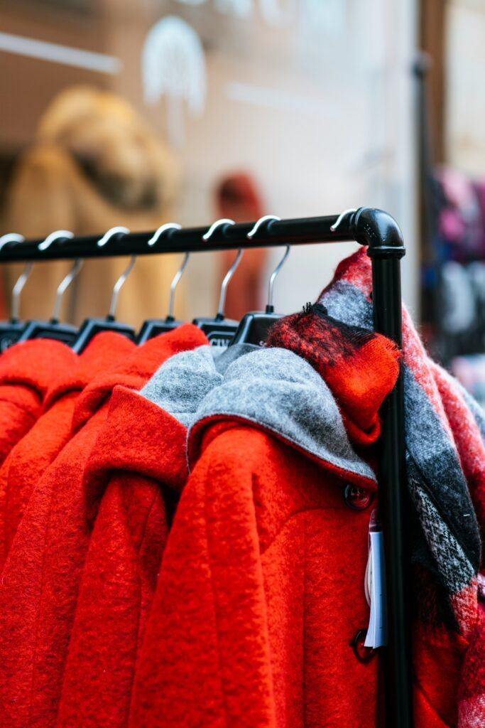 History of Winter Fashion Trends and How They Evolved Today! 10 Two women showcasing winter fashion: one wearing a brown teddy coat with a red-and-green plaid scarf in a snowy outdoor setting, and another walking in an urban street wearing a long red coat, white turtleneck, gray pants, and carrying a white handbag.History of Winter Fashion Trends