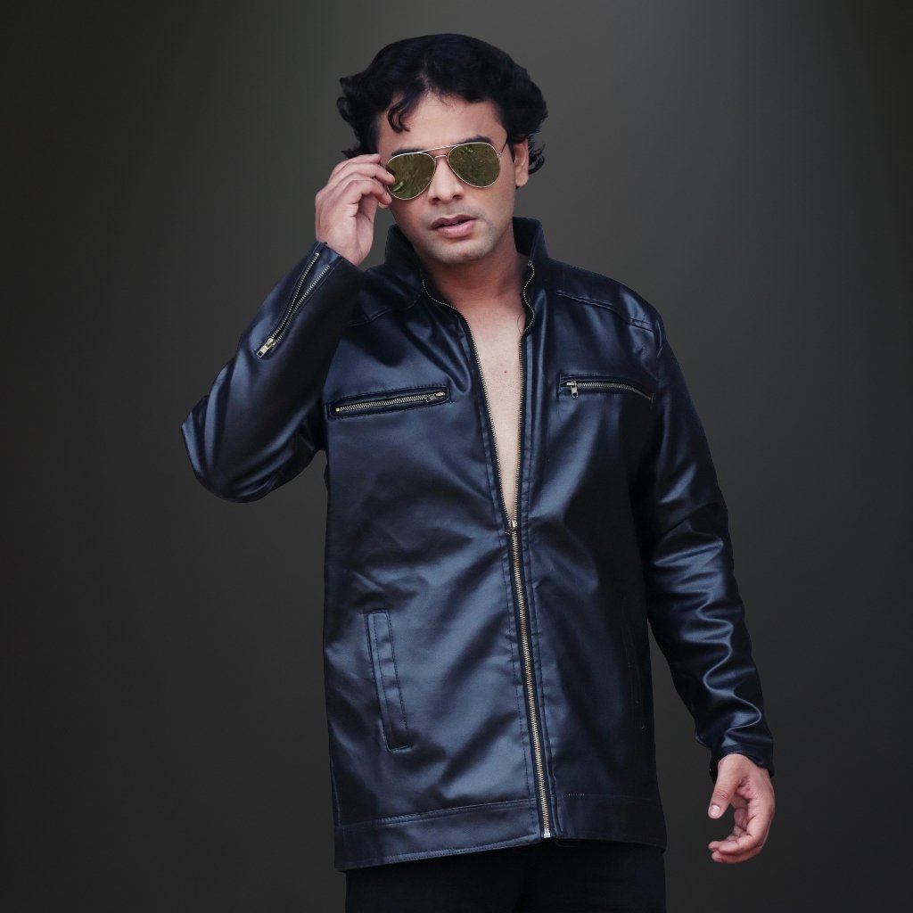 Alt text (for screen readers): A man wearing a dark, glossy leather parka jacket with a front zipper and zippered chest pockets, posing with sunglasses and one hand adjusting them.

