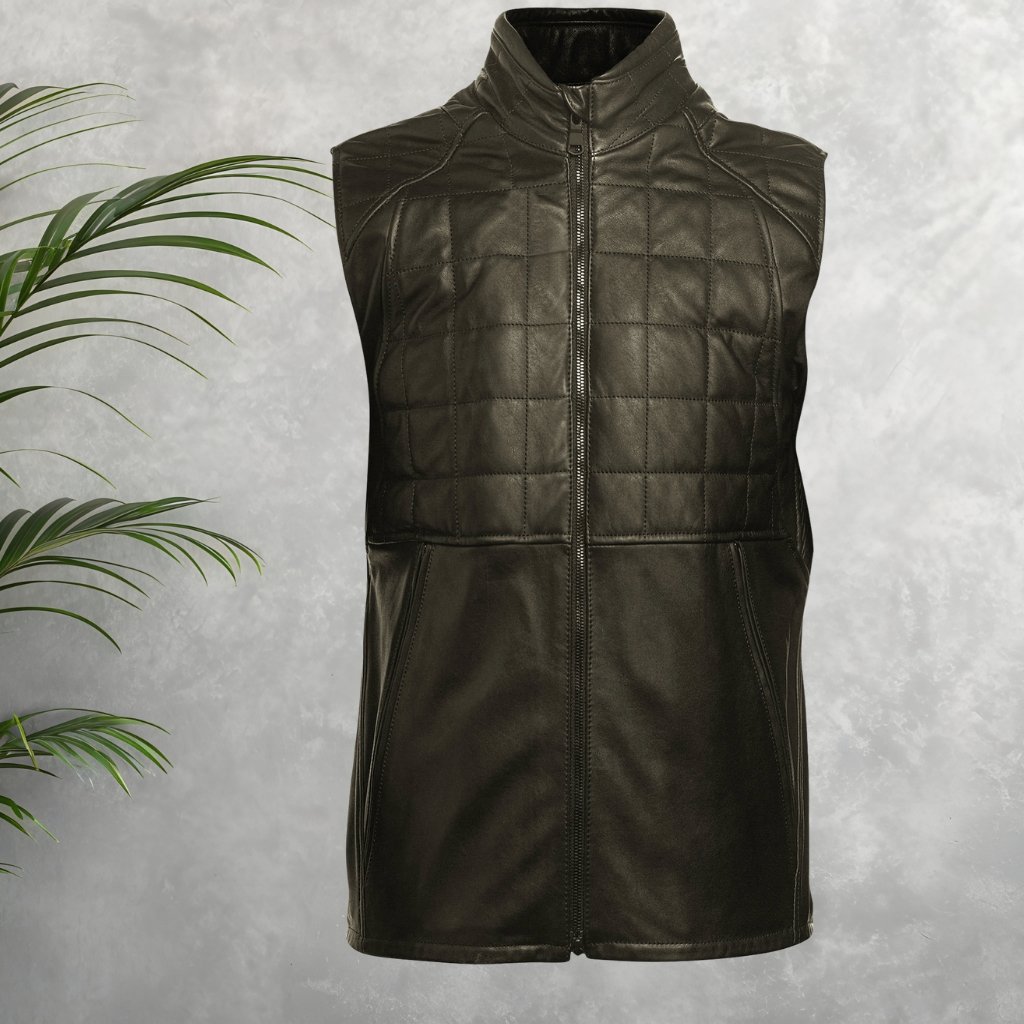 A sleeveless black quilted jacket with a front zipper, high collar, and clean lines, displayed on a neutral backdrop with a green plant to the left.