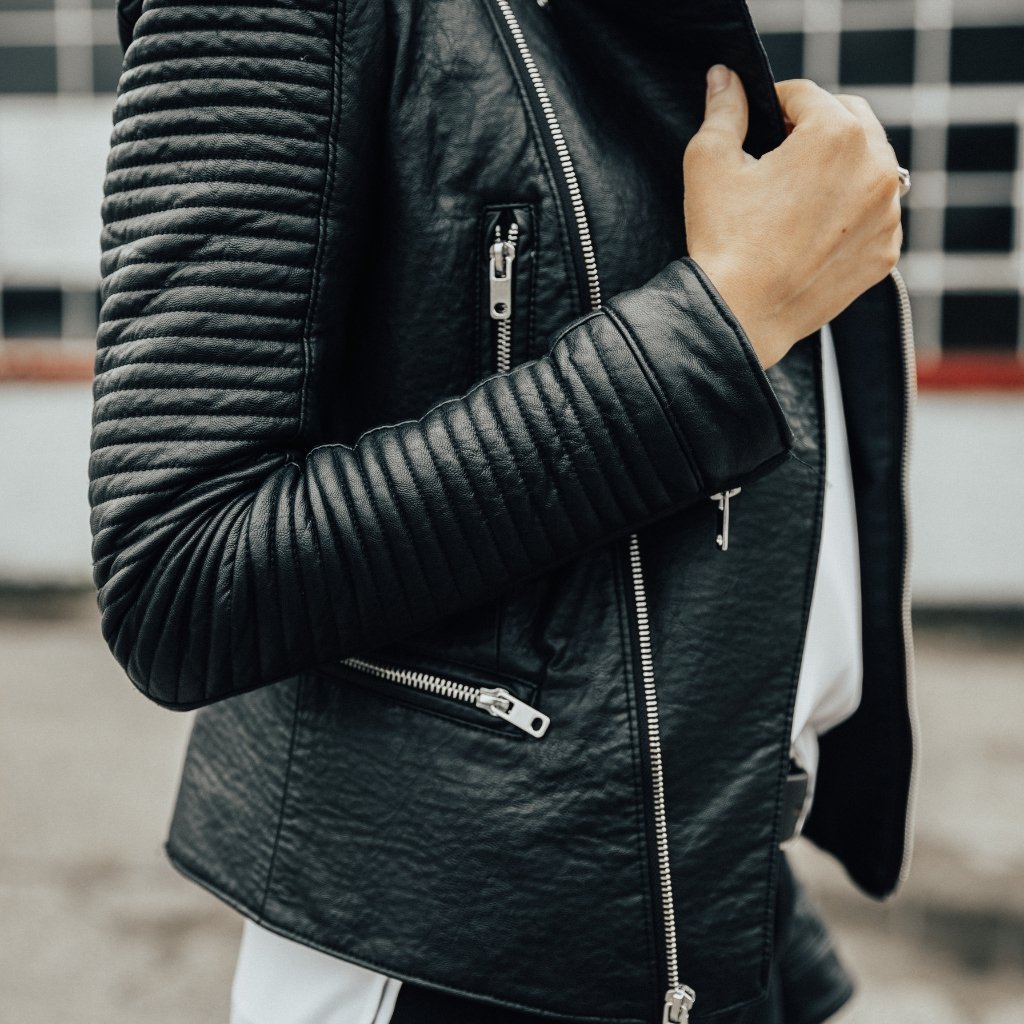 Close-up of a black leather blazer with quilted shoulder details, visible zippers and a notched lapel.