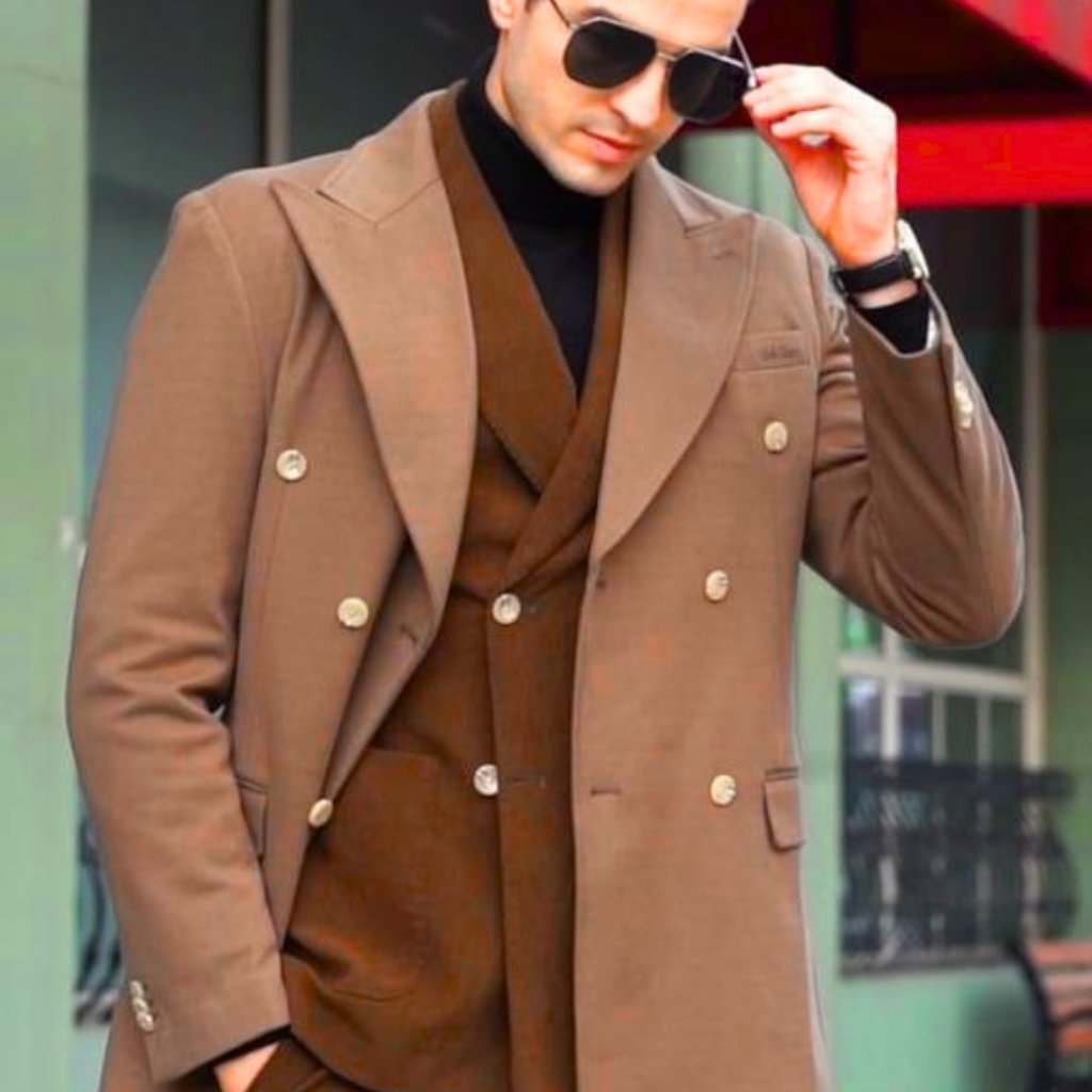 Elegant Topcoat Timeless Statement of Style & Sophistication 10 A stylish man wearing a tan double-breasted overcoat and a brown suit underneath, black turtleneck, dark sunglasses, and a wristwatch, posing with one hand adjusting his sunglasses.