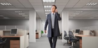 Modern Slim Topcoat: Elevate Your Look with Tailored Style A man in a long coat walks through an empty office while talking on a mobile phone. Modern Slim Topcoat