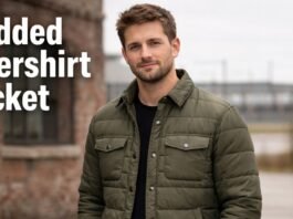 A man wearing an olive padded overshirt jacket standing outdoors near a brick building.