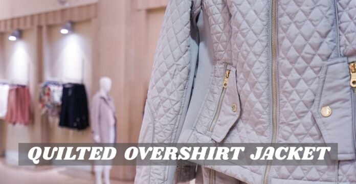 A quilted overshirt jacket in a light gray color with visible zipper and pocket details, displayed in a store setting.