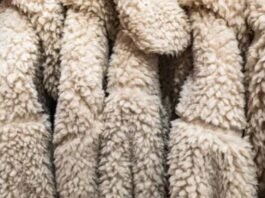 Close-up of beige sherpa fleece fabric with a thick, soft, curly texture arranged in folded layers.Is Pure Wool Worth It?