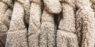 Is Pure Wool Worth It? Key Benefits You Need to Know Today Close-up of beige sherpa fleece fabric with a thick, soft, curly texture arranged in folded layers.Is Pure Wool Worth It?