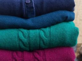 Stack of folded wool sweaters in rich winter colors, showcasing soft texture and cozy knit fabric.
