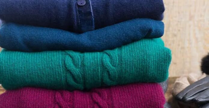 Stack of folded wool sweaters in rich winter colors, showcasing soft texture and cozy knit fabric.