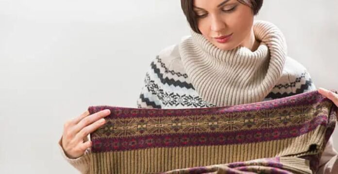 Woman examining the fabric of a patterned wool sweater, checking its texture and quality.Does Shetland Wool Itch?