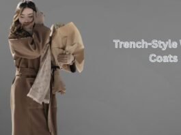 Woman wearing a beige trench-style winter coat with a scarf, holding a bouquet against a minimalist grey background.Trench-Style Winter Coats