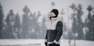 Military-Inspired Winter Jackets: Timeless Style Guide 2025 Man wearing a gray and black insulated winter jacket standing outdoors in a snowy landscape.Military-Inspired Winter Jackets