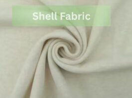 A close-up of light beige shell fabric arranged in a swirl pattern with the text “Shell Fabric” displayed in a green box at the top.Does Shell Fabric