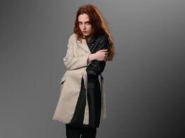 Woman wearing a beige and black color-block coat with leather sleeve against a grey background.Is a Long Parka Coat Worth It?