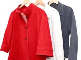 Three women’s jackets hanging on wooden hangers, featuring a bright red coat in front, followed by a white jacket and a dark grey jacket against a plain white background. Boiled Wool Jacket
