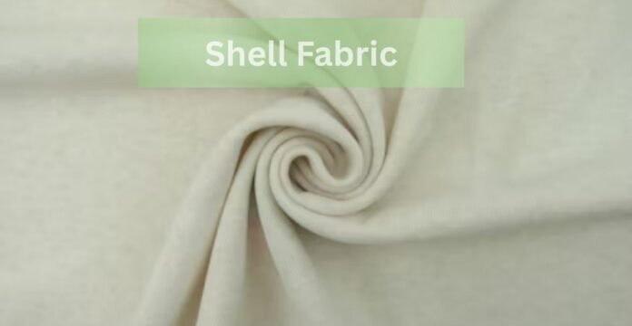A close-up of light beige shell fabric arranged in a swirl pattern with the text “Shell Fabric” displayed in a green box at the top.Does Shell Fabric