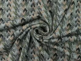 Close-up of patterned shell fabric with a textured weave in muted green, beige, and black tones, arranged in a swirl.Is Herringbone Wool Worth It?