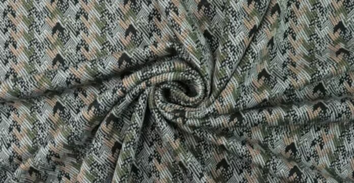 Close-up of patterned shell fabric with a textured weave in muted green, beige, and black tones, arranged in a swirl.Is Herringbone Wool Worth It?