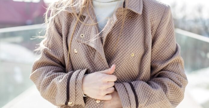 Close-up of a person wearing a brown quilted coat, holding the lapels with both hands. Stylish Women Topcoat Jackets