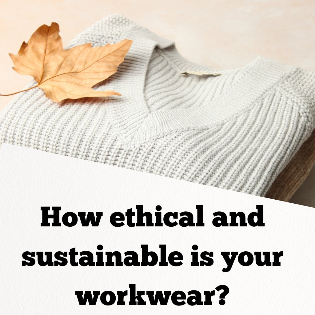 Close-up of a folded light gray knit sweater with a dried autumn leaf resting on top.