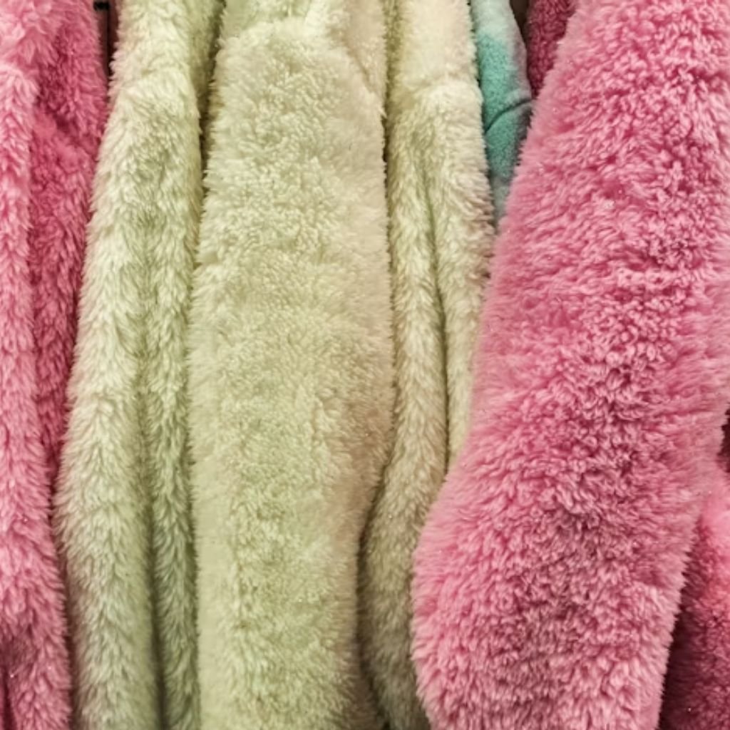 A woman wearing a brown double-breasted wool coat with a wide collar, styled with patterned black leggings.Teddy Coats