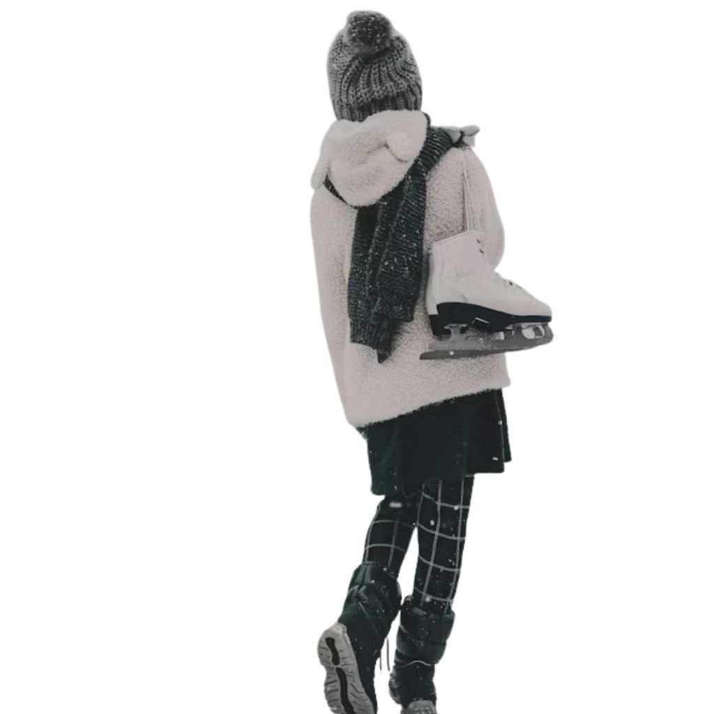 A woman walking on snow-covered railway tracks wearing a cozy winter outfit with a large green plaid scarf, white sweater, black skirt, tights, and boots.Monochrome winter outfits
