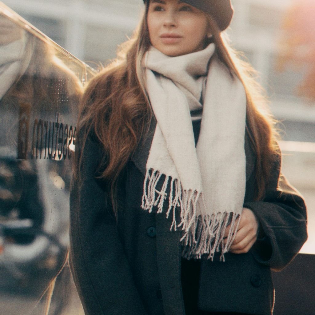 Person wearing a bright pink, cinched winter jacket posing in front of a metallic silver decorative background.Military-Inspired Winter Jackets