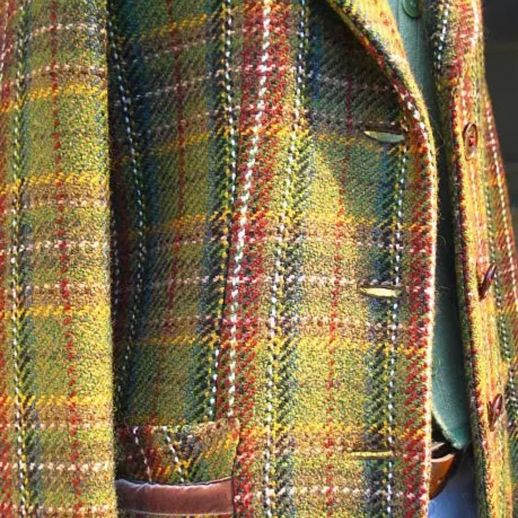 Close-up of a multicolored tweed jacket showing a plaid pattern, textured wool fabric, and brown buttons.Does Shetland Wool Itch?