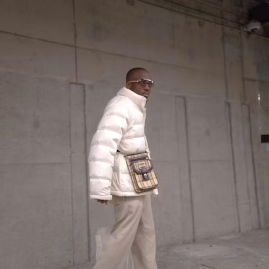 A color-blocked hooded windbreaker featuring white, gray, black, and yellow panels, laid flat on a concrete surface.Why Oversized Padded Jackets