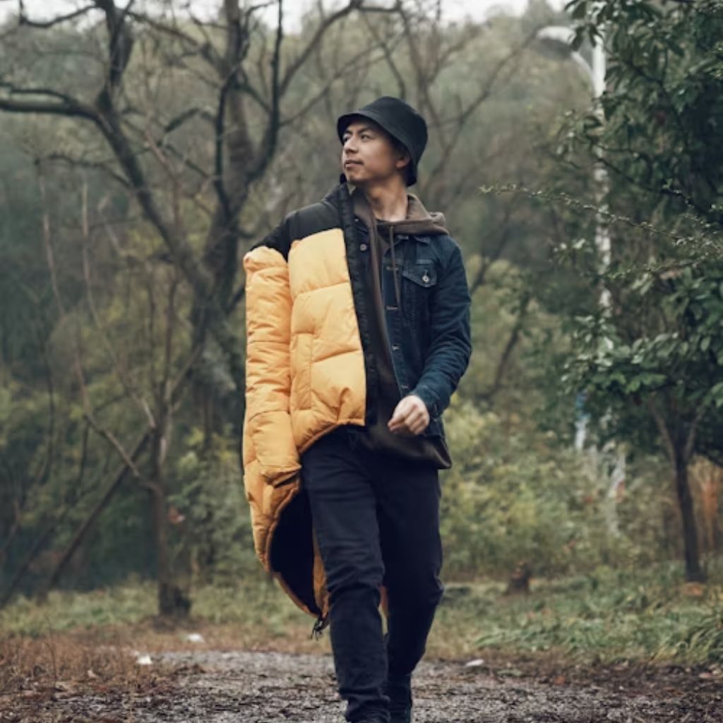 Person wearing an oversized olive-green padded jacket against a light blue background.Why Oversized Padded Jackets