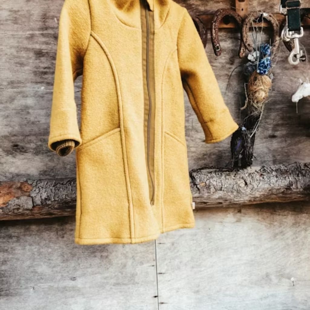 Person wearing a deep red zip-up jacket over a white turtleneck, holding matching red gloves.The Wool Peacoat Comeback: