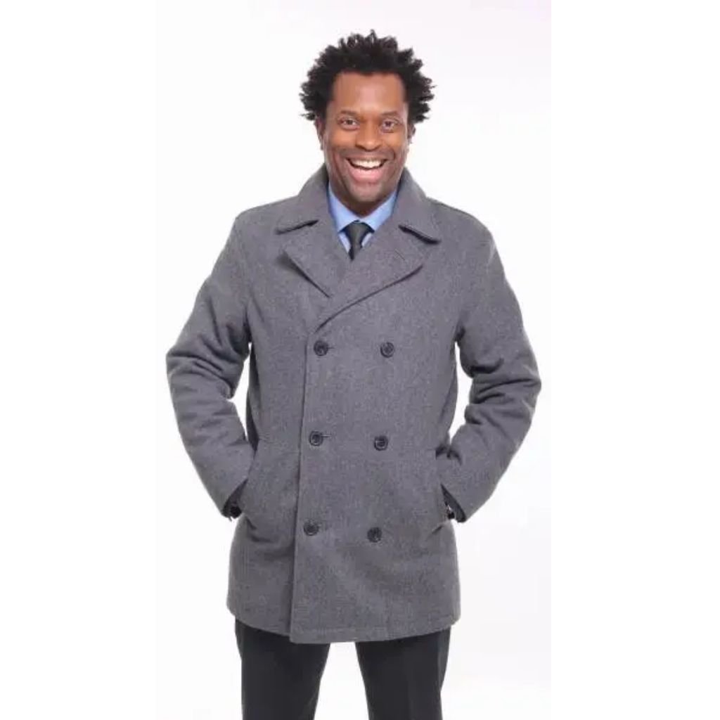 A man wearing a brown shearling-lined coat and mustard turtleneck stands outdoors, leaning against a black iron railing.The Wool Peacoat Comeback: