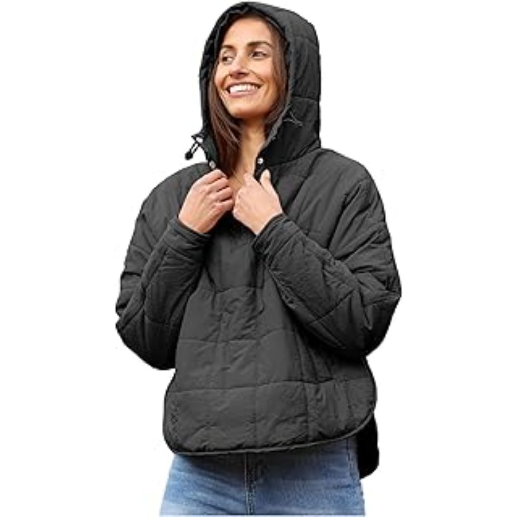 A smiling woman wearing a black quilted hooded jacket stands with her hands adjusting the collar, posing confidently against a plain white background.Why Oversized Padded Jackets