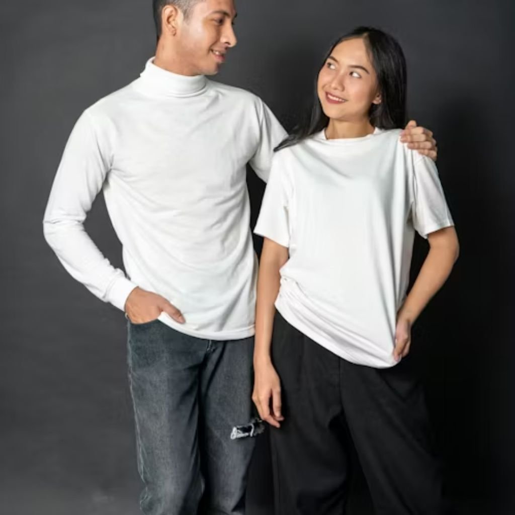 Two people wearing white tops stand side by side against a dark background, smiling at each other, with one person’s arm resting on the other’s shoulder.Lambswool Clothing