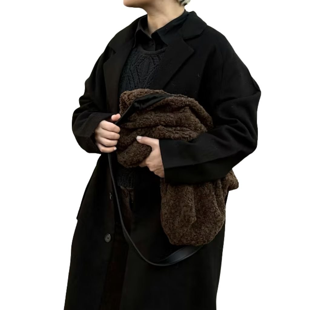 A person wearing a black winter parka with a faux-fur trimmed hood, standing against a plain white background and holding colorful gloves.Why Victorian-Era Winter Coats