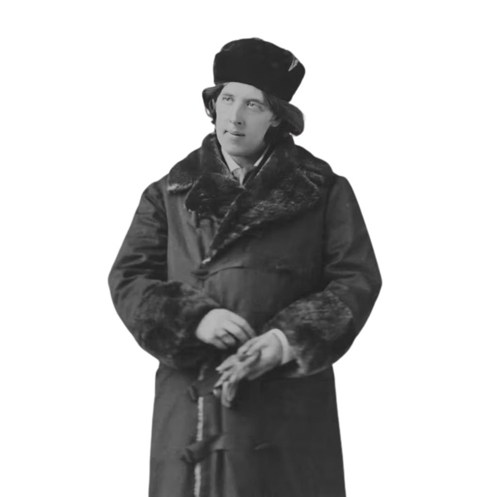 A person wearing a long fur-trimmed winter coat and a fur hat stands looking slightly to the side with hands clasped together.Why Victorian-Era Winter Coats