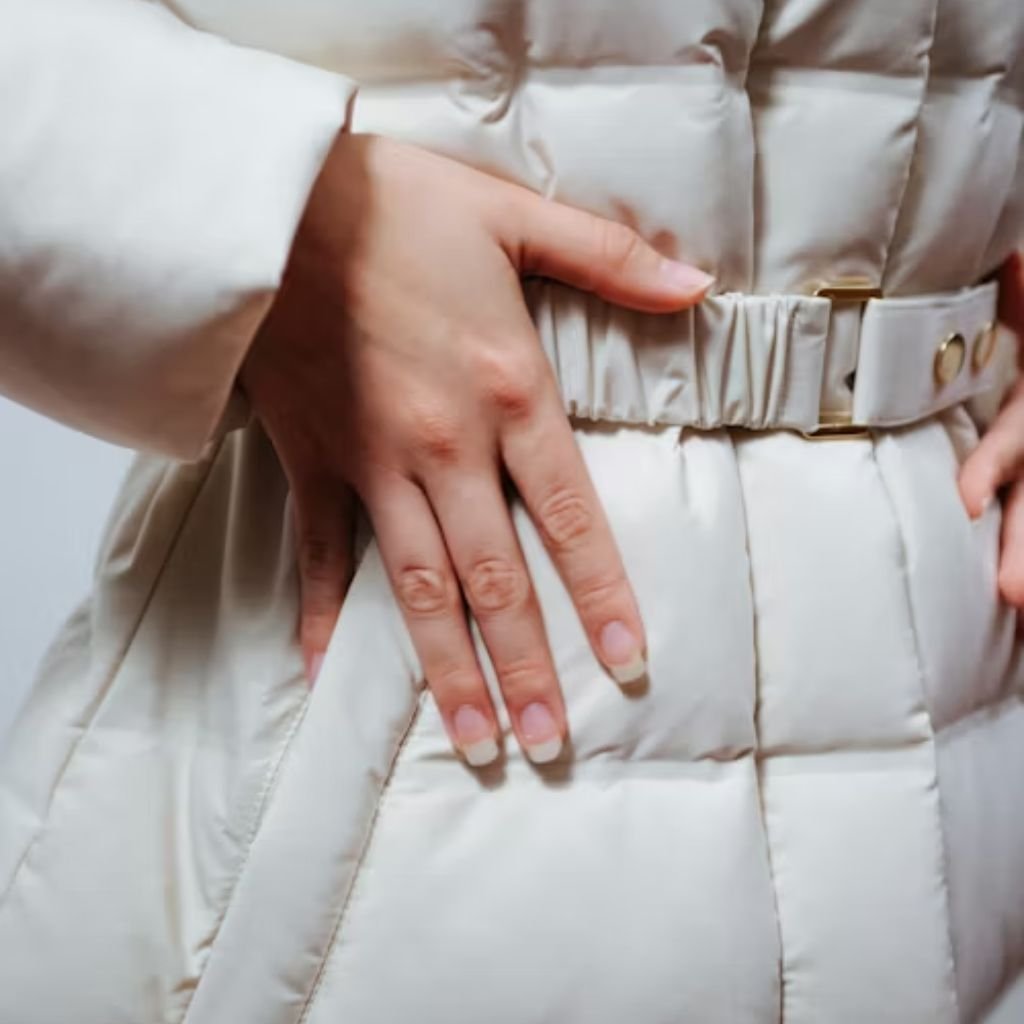 Two women wearing belted winter coats, one in a brown hooded parka and the other in a long taupe belted puffer coat, styled for cold weather.Belted Winter Coats