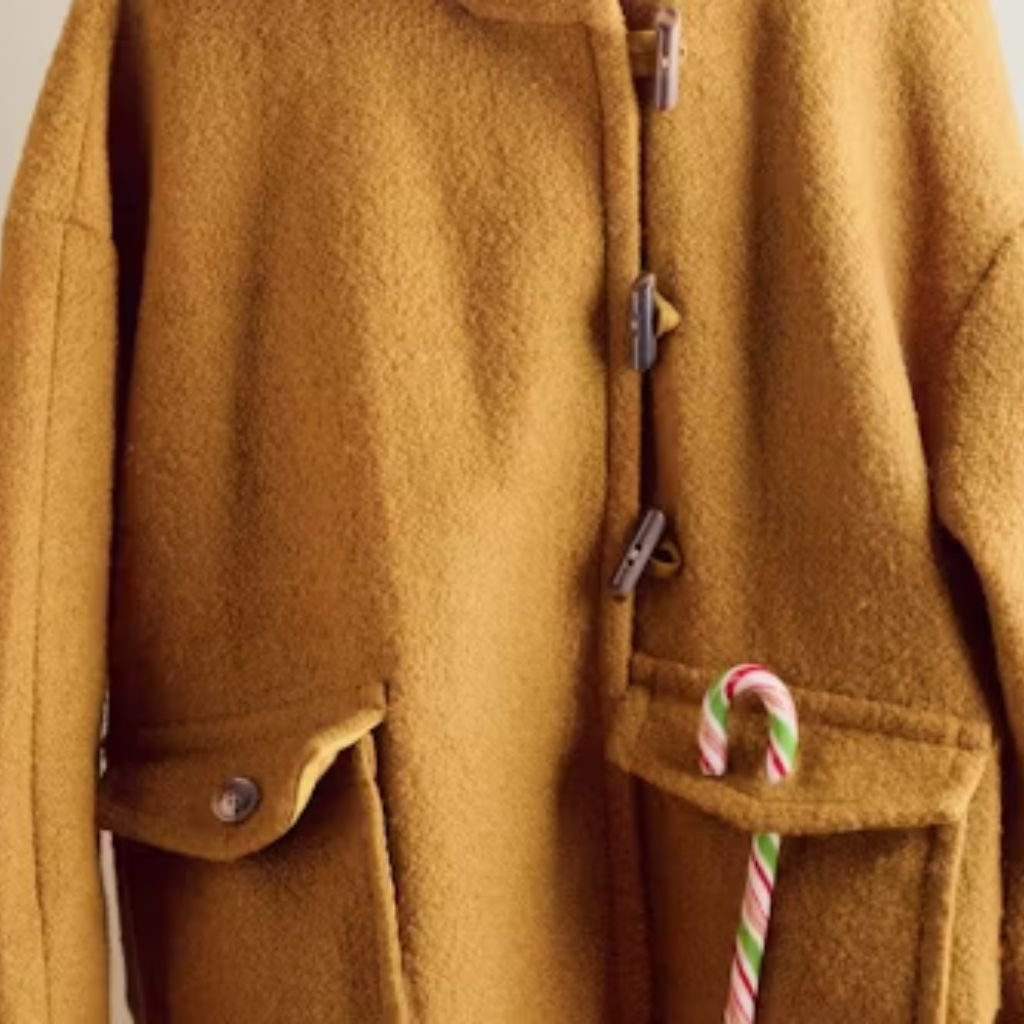 A woman wearing a brown double-breasted wool coat with a wide collar, styled with patterned black leggings.Teddy Coats