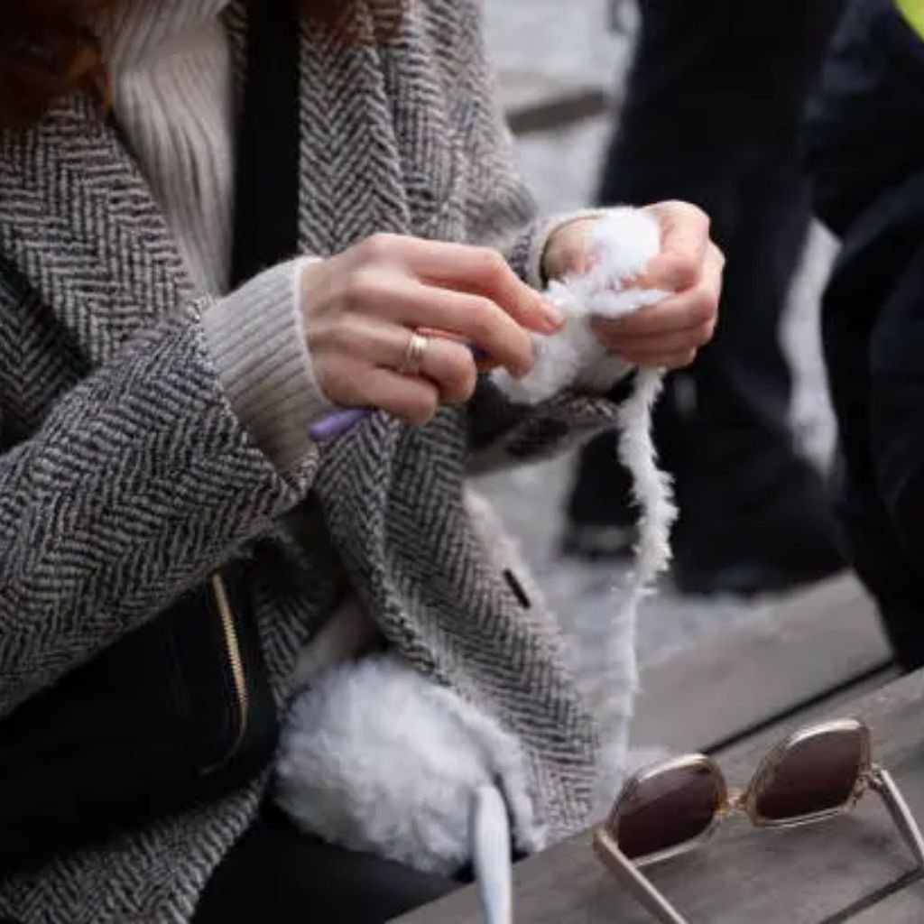 Mustard-yellow hooded coat hanging on a rustic wooden wall with metal hooks and rope.Is Herringbone Wool Worth It?