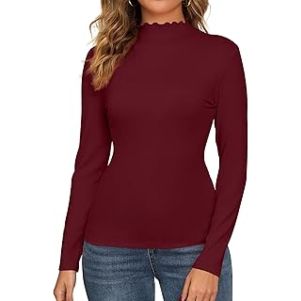 The image features a woman posing gracefully against a soft, neutral background. She is wearing a stylish fall outfit that includes a dark ribbed sleeveless knit top layered over a houndstooth-patterned long-sleeve blouse. Her hair is neatly styled in a low bun with a few loose strands framing her face. With one arm lifted over her head, she gives a relaxed and confident expression, showcasing both the outfit’s texture and its modern, minimalistic aesthetic.Why Mock neck turtlenecks