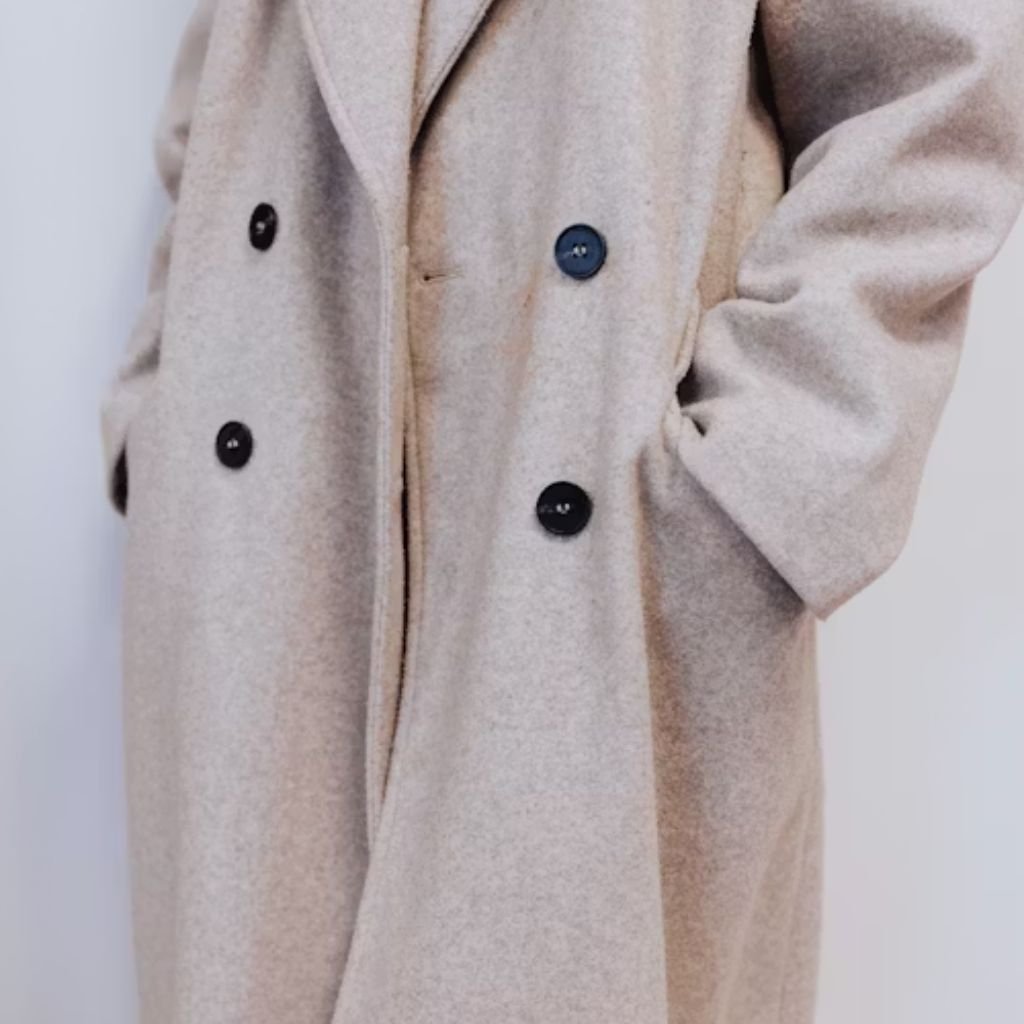 Close-up of a light beige double-breasted coat with dark buttons and a hand in the pocket.Is a Long Parka Coat Worth It?